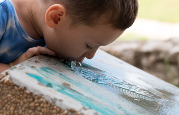 istock Child drinks cold water from a cooler in a park 1165589109