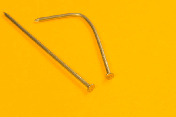 istock Metal nails isolated on yellow background. working tools 1165590688