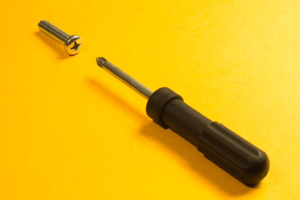istock Screwdriver with screw on a yellow background 1165590940