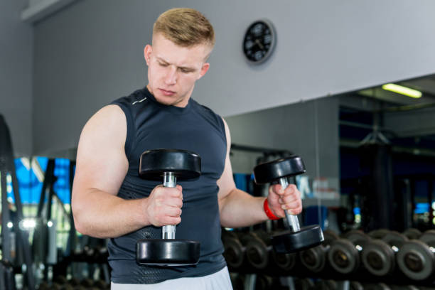 istock man doing exercise with dumbbells in the gym 1165591699