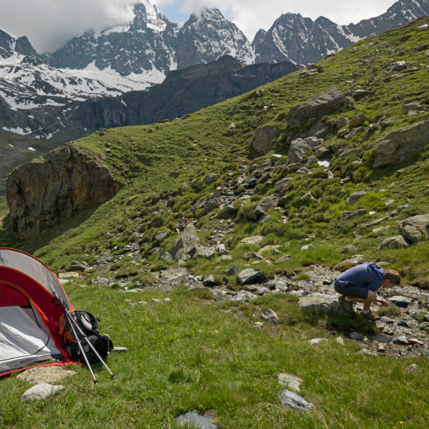 istock Young man camping in tent on a mountain meadow 1165602572