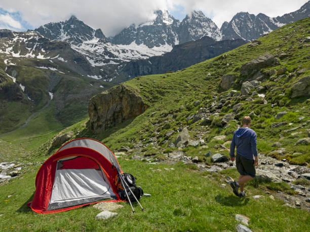 istock Young man camping in tent on a mountain meadow 1165602587