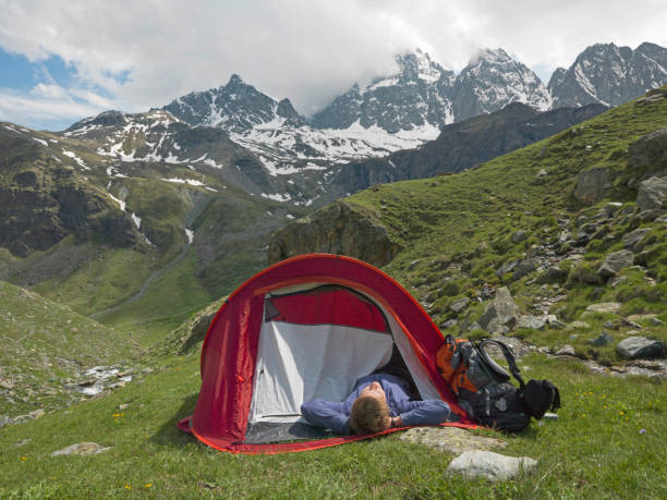 istock Young man camping in tent on a mountain meadow 1165602604