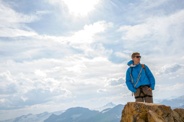 istock Climber stands on summit in mountains and sunlight 1165602640