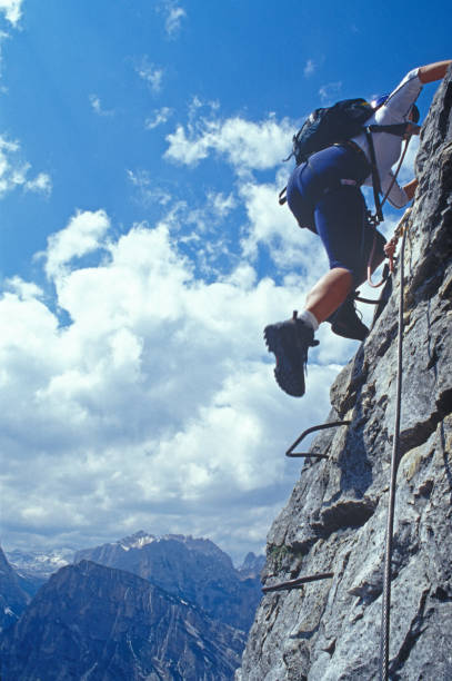 Woman climbs via ferrata above mountains