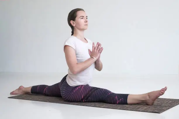 Photo of European mature woman practicing yoga doing Hanumanasana