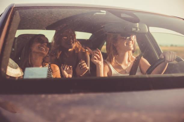 istock Girlfriends having fun while driving together in a car in warm summer sunshine 1165610657