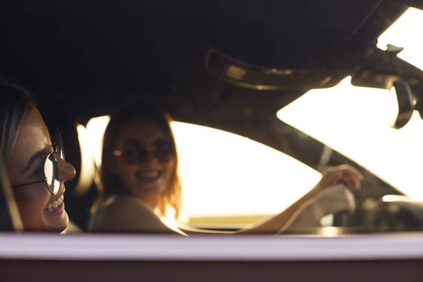 istock Two cheerful young girlfriends having a laugh while driving on a summer road trip together 1165610678