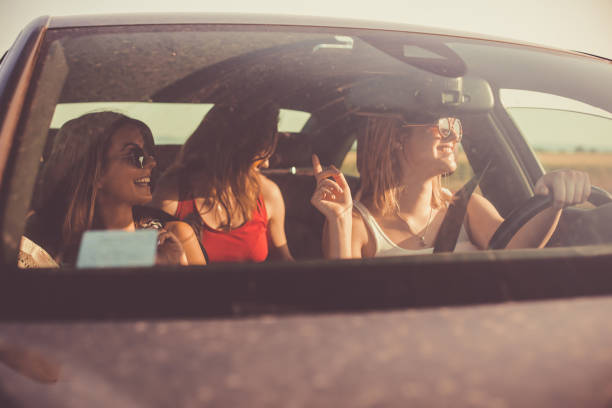 istock Three cheerful young women dancing while driving in a car 1165610789