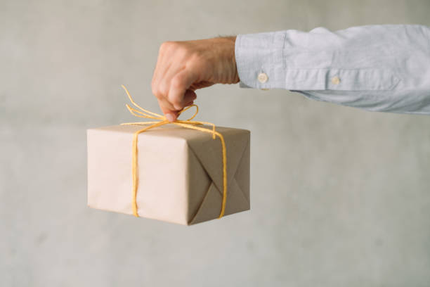 istock goods delivery service beige gift box man hand 1165610822