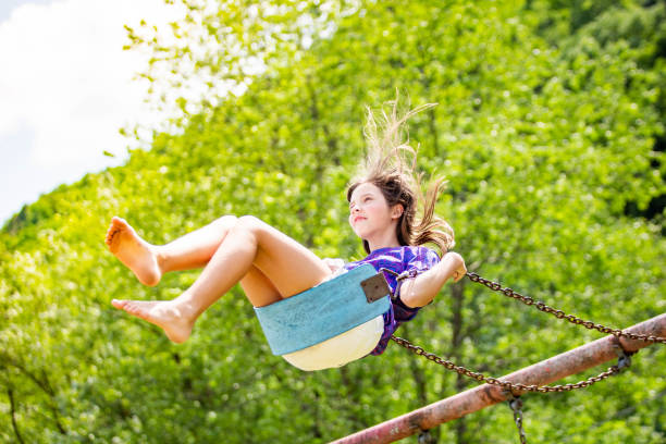 istock Young girl swinging high bright summer day 1165616869