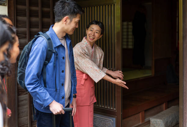 伝統的に服を着た日本人女性が旅館を訪れる人にお辞儀をする - 旅館 ストックフォトと画像