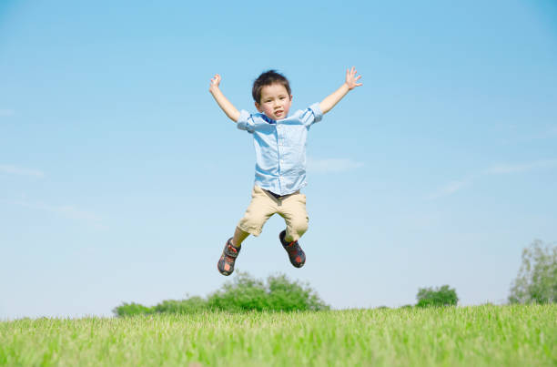 フィールドで遊ぶ日本人の少年 - ジャンプする ストックフォトと画像