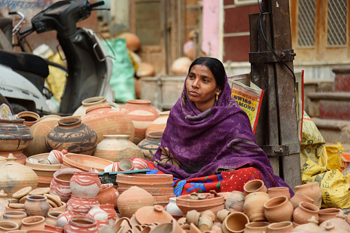 Bikaner, India - February 11, 2019: Indian woman selling clay pots on local market in Bikaner. Rajasthan