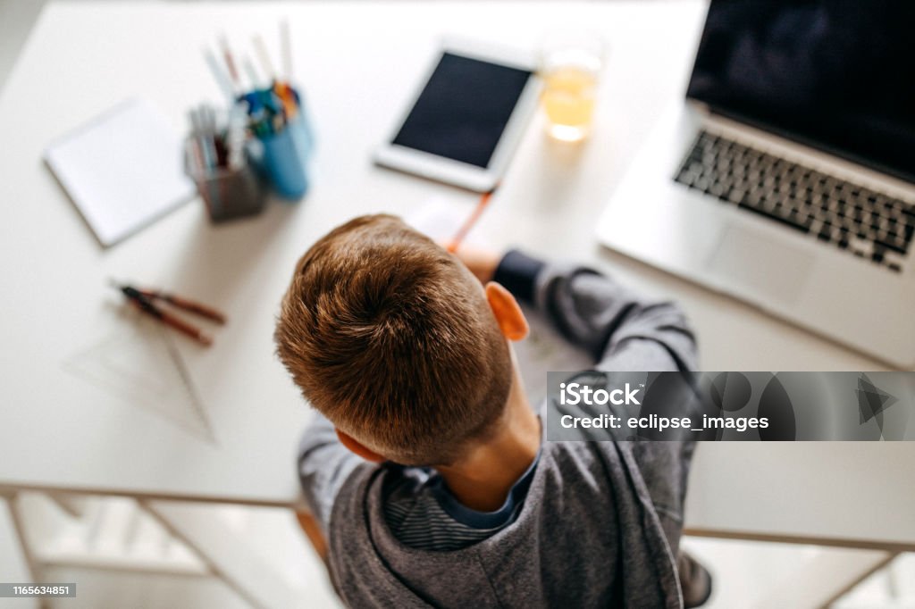 One more question to be answered Young boy sitting in his room and doing homework Child Stock Photo