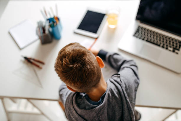 One more question to be answered Young boy sitting in his room and doing homework home schooling homework computer learning stock pictures, royalty-free photos & images