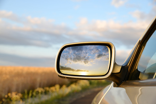 sideview mirror of a car at sunset.