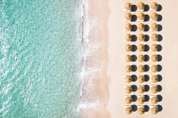 Photo of View from above, stunning aerial view of an amazing white beach with beach umbrellas arranged symmetrically and a beautiful turquoise clear water. Sardinia, Italy.