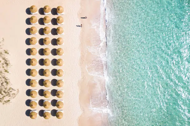 Photo of View from above, stunning aerial view of an amazing white beach with beach umbrellas arranged symmetrically and a beautiful turquoise clear water. Sardinia, Italy.