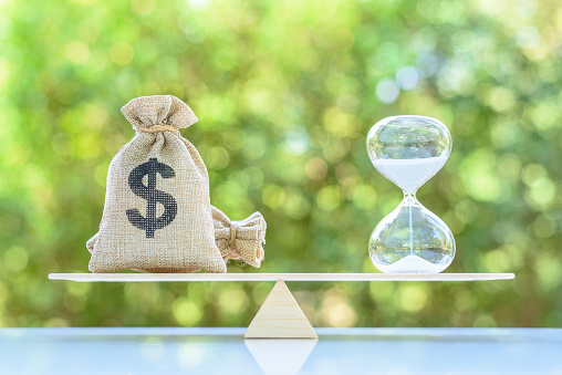 Time value of money, asset growth over time, financial concept : Dollar bags, sand clock or hourglass on a balance scale in equal position, depicts investment in long-term equity for more money growth