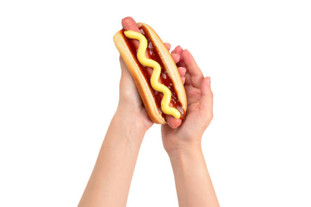 Hot dog in woman hand isolated on white background. Copy space.