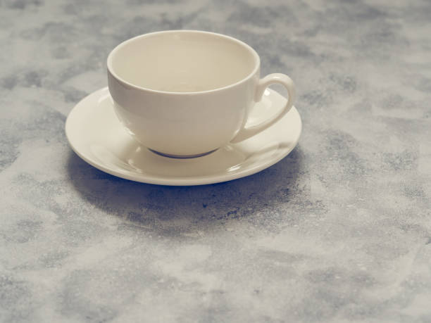 istock Empty white cup with saucer on a gray concrete background 1165645408