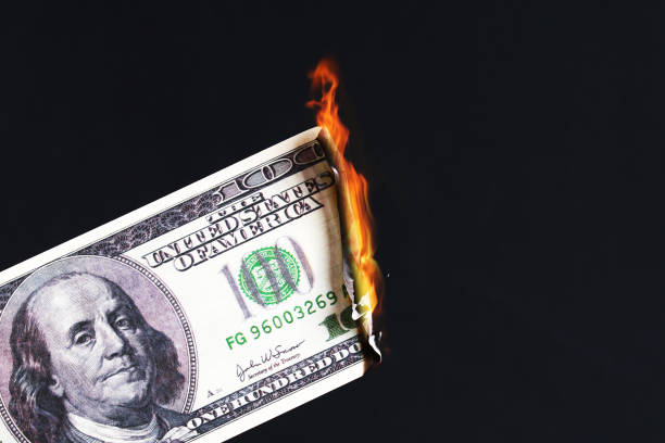 istock one hundred American dollar burning in fire flame. collapse of dollar. Devaluation. Falling currency 1165648829