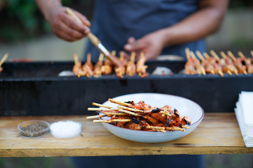 Kebabs barbecue preparation with a male brushing sticky sauce onto the meat on sticks at an event wedding outdoors for canapés Cape Town South Africa