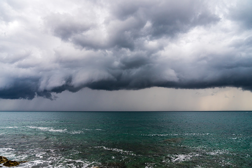 Montenegro, Spectacular storm front of dark dramatic sky with heavy rain coming fast over azure ocean water of budva coast in summer