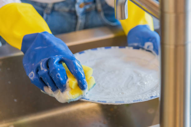 istock Cleaning dishware kitchen - The dish-washing process - Blue and yellow plastic gloves with a lot of foam 1165651464