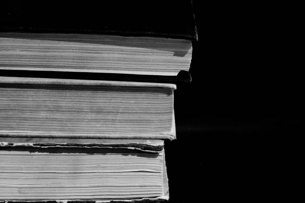 istock Stack of old books on black background. Black and white photo. 1165655898