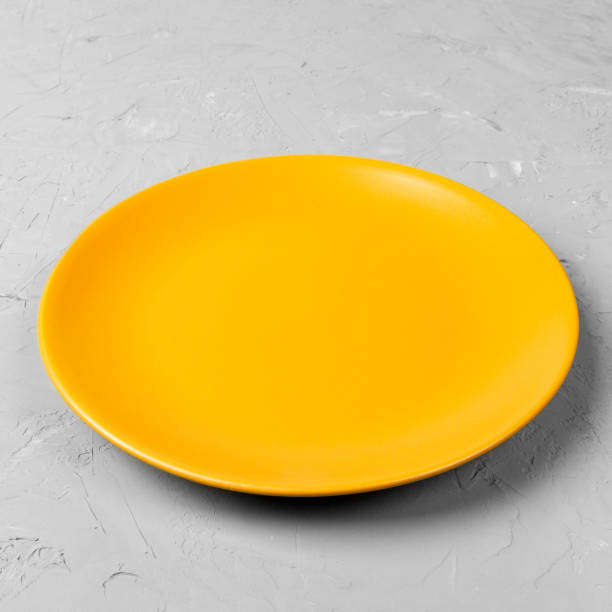 istock Yellow Round Plate on grey cement table background. Top view, template for your design 1165657132
