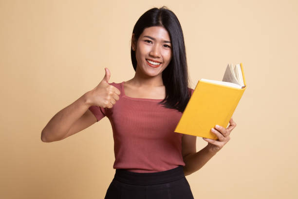 istock Young Asian woman thumbs up with a book. 1165660111