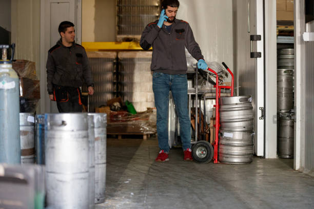 istock Workers in brewery warehouse by kegs on push cart 1165660816