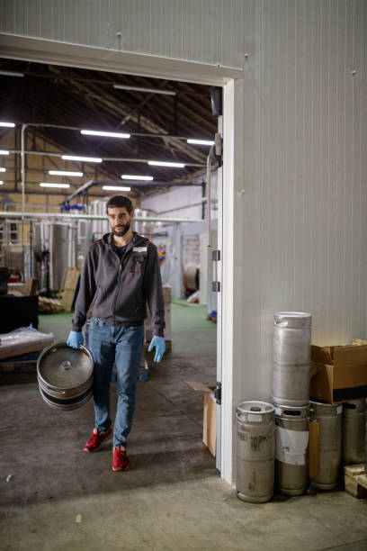 istock Worker in brewery moving aluminum barrels 1165661206