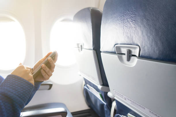 istock Hand using smartphone and window in airplane with seats in the cabin 1165661430
