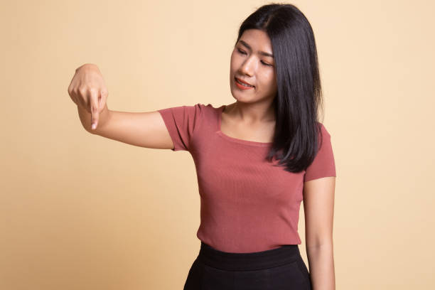 istock Beautiful young Asian woman point down to blank space. 1165662216