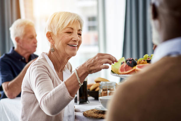 Let me try some of these Shot of a cheerful group of senior people talking and enjoying breakfast together at home dining stock pictures, royalty-free photos & images