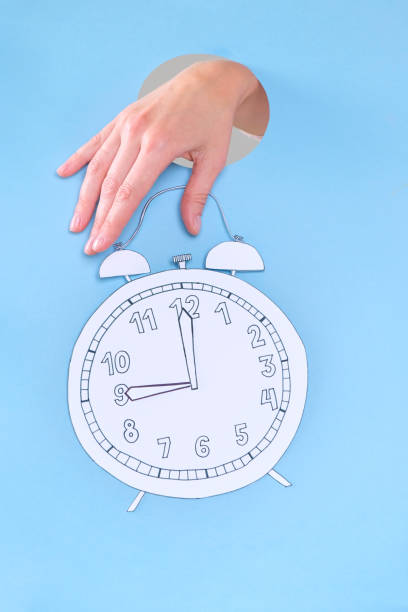 istock Women hand holding alarm clock on blue background. 1165664180