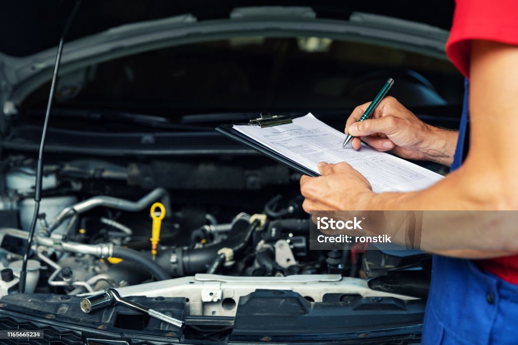 mantenimiento y reparación del coche - mecánico escribiendo papel de lista de verificación en el portapapeles - Foto de stock de Coche libre de derechos