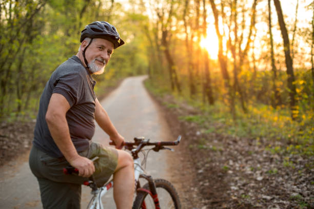 uomo anziano sulla sua mountain bike all'aperto - anziani attivi foto e immagini stock