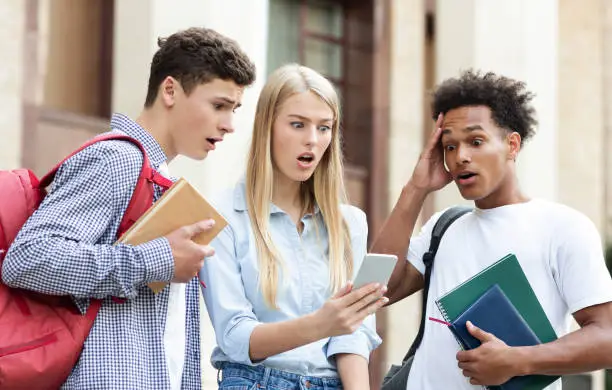 Photo of Students checking exam results on smartphone, resting in campus