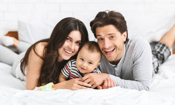 istock Millennial parents cuddling with baby son on bed 1165675419