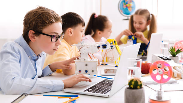 Schoolboy programming diy robot with laptop at stem lesson Schoolboy programming diy robot with laptop, studying modern technologies at stem lesson schoolboy stock pictures, royalty-free photos & images