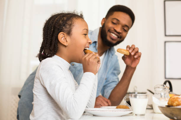 istock Father and daughter eating cookies, drinking milk 1165677390