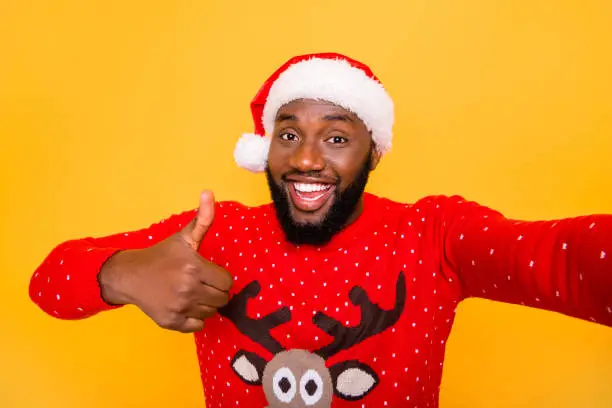 Self-portrait of his he nice attractive cheerful cheery positive guy wearing celebratory, costume December showing thumbup advert isolated over bright vivid shine yellow background
