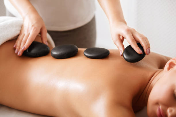 istock Masseur placing stones on woman's back, closeup 1165680860