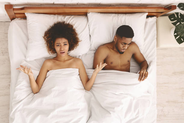 расстроенная пара влюбленных, лежащих на кровати. семейный конфликт. - sexual activity black couple african descent стоковые фото и изображения