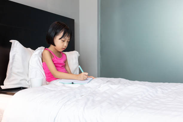 istock Asian Little Chinese Girl doing homework in bed 1165681307