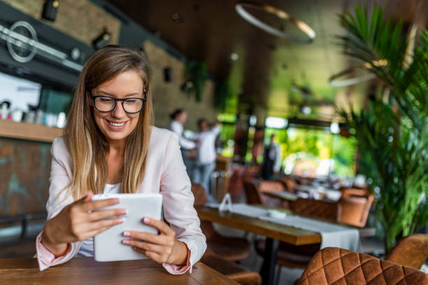 ładna młoda kobieta manager za pomocą nowoczesnego tabletu cyfrowego w kawiarni - reading newspaper 30s adult zdjęcia i obrazy z banku zdjęć